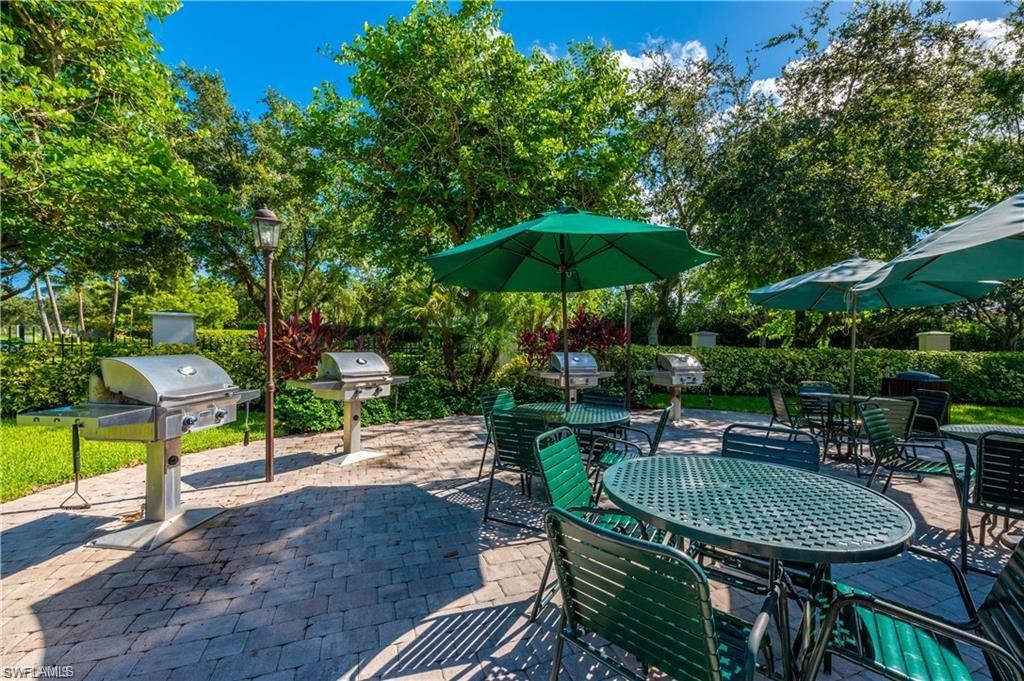 7940 Mahogany Run Lane, Unit 623 Naples, FL 34113 - Photo 24 of 25 a view of a table and chairs under an umbrella in backyard