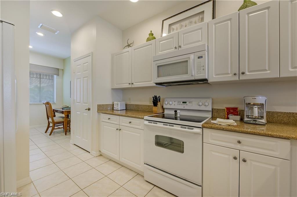 7940 Mahogany Run Lane, Unit 623 Naples, FL 34113 - Photo 7 of 25 a kitchen with granite countertop white cabinets and white appliances