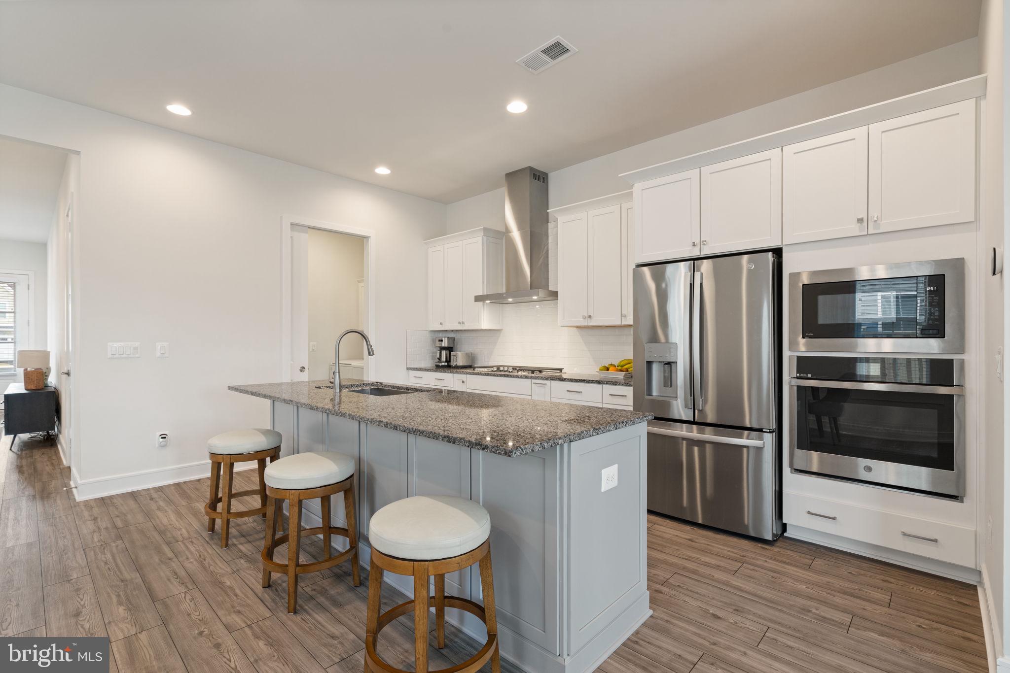 14712 Grand Cru Loop Gainesville, VA 20155 - Photo 11 of 46 a kitchen with stainless steel appliances granite countertop a sink a stove a refrigerator and island with wooden floor