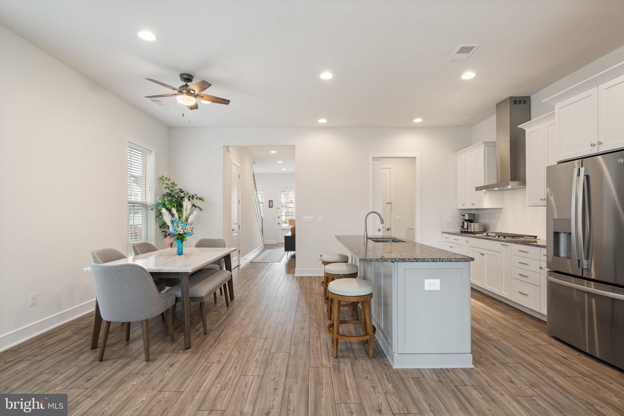14712 Grand Cru Loop Gainesville, VA 20155 - Photo 14 of 46 a kitchen with a dining table chairs refrigerator and cabinets
