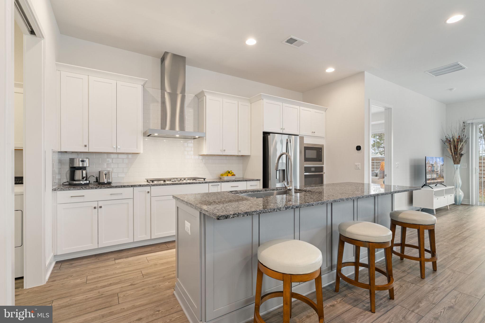 14712 Grand Cru Loop Gainesville, VA 20155 - Photo 6 of 46 a kitchen with stainless steel appliances granite countertop a table chairs sink and cabinets