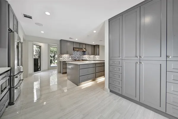 a large white kitchen with a large window a sink and stainless steel appliances