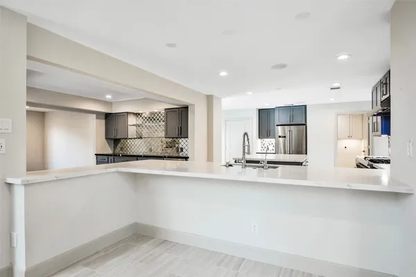 a large white kitchen with a refrigerator a sink and a counter top space