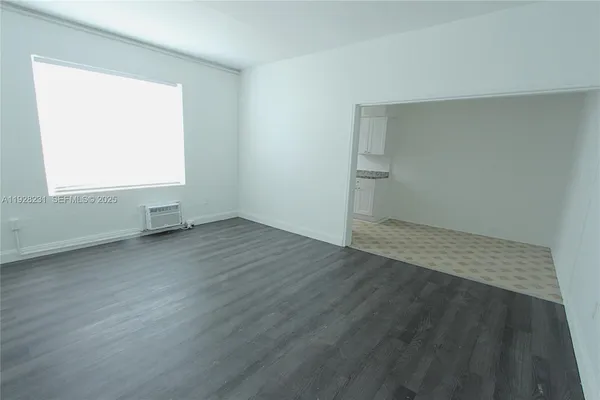 a view of a refrigerator in kitchen and an empty room