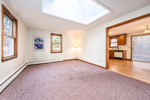 a view of an empty room with a window and wooden floor