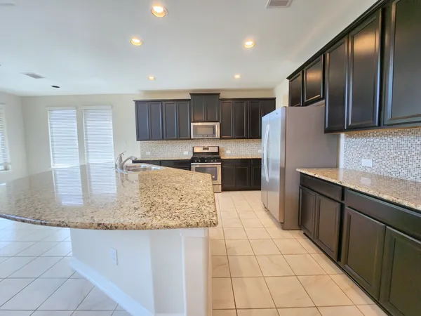 a kitchen with stainless steel appliances granite countertop a sink and a refrigerator