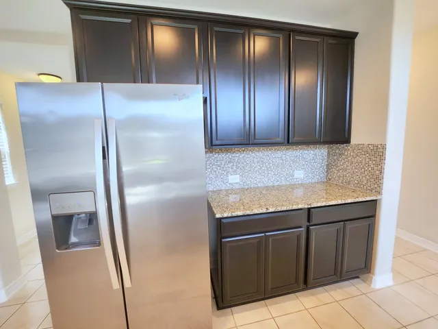 a view of a refrigerator in kitchen and stainless steel appliances wooden cabinet