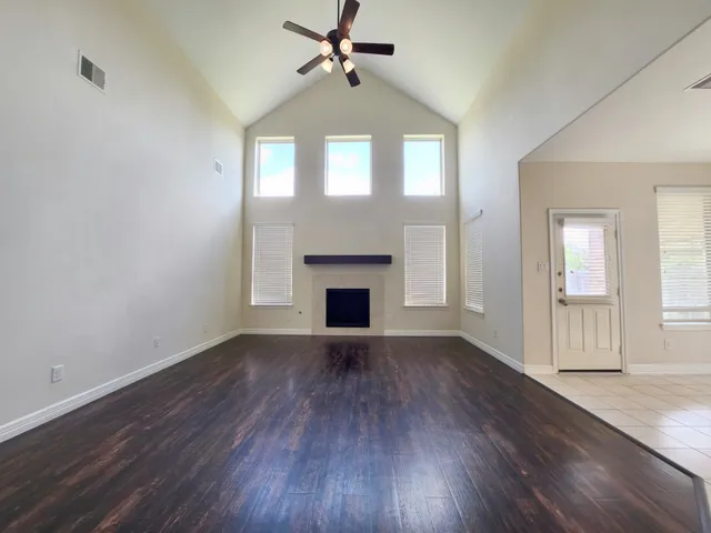 an empty room with wooden floor fireplace and windows