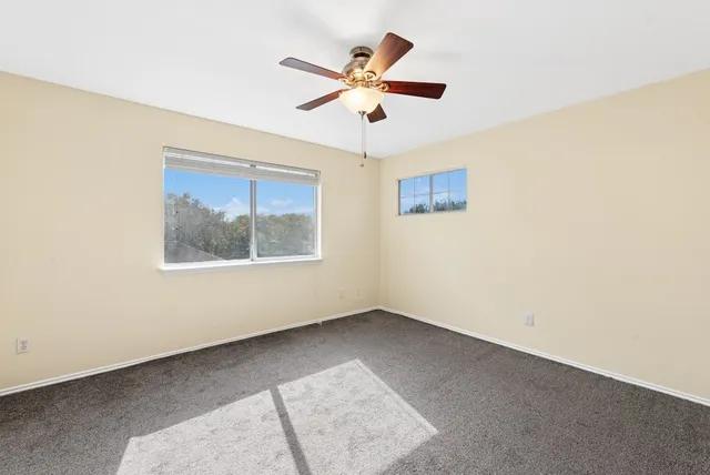 an empty room with a window and a ceiling fan