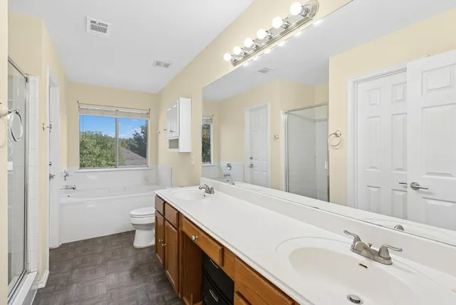 a bathroom with a double vanity sink a large mirror a bathtub and next to a window