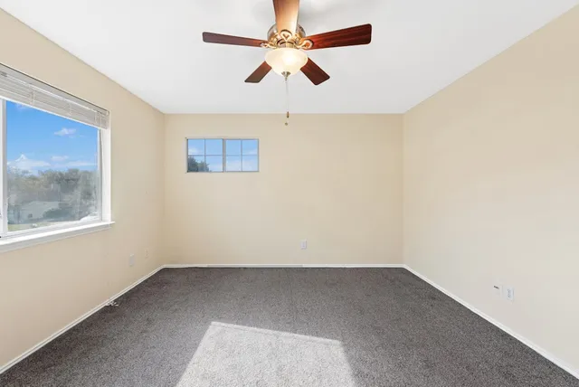 an empty room with a window and a ceiling fan