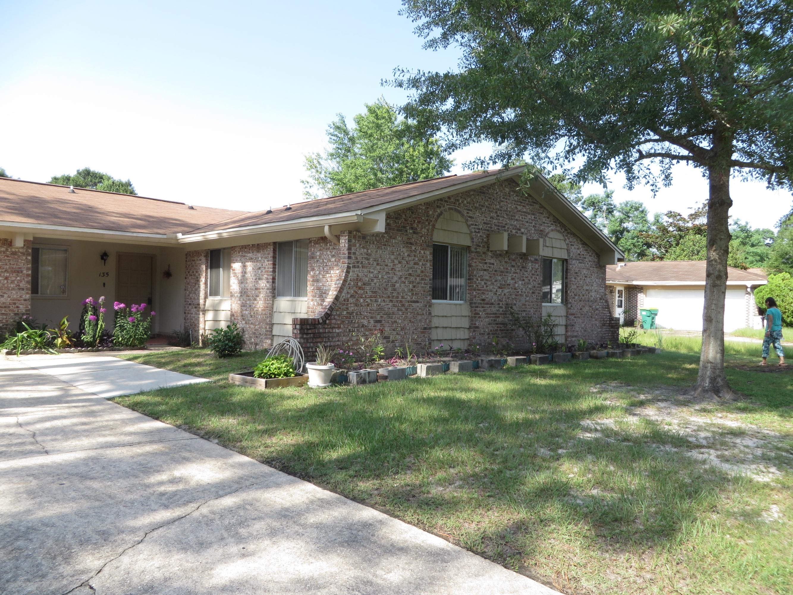 135 Perdido Circle Niceville, FL 32578 - Photo 2 of 28 a backyard of a house with plants and large tree