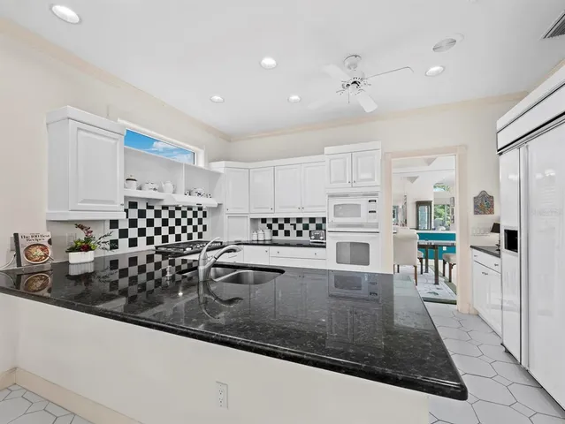 a kitchen with granite countertop a sink a stove and cabinets