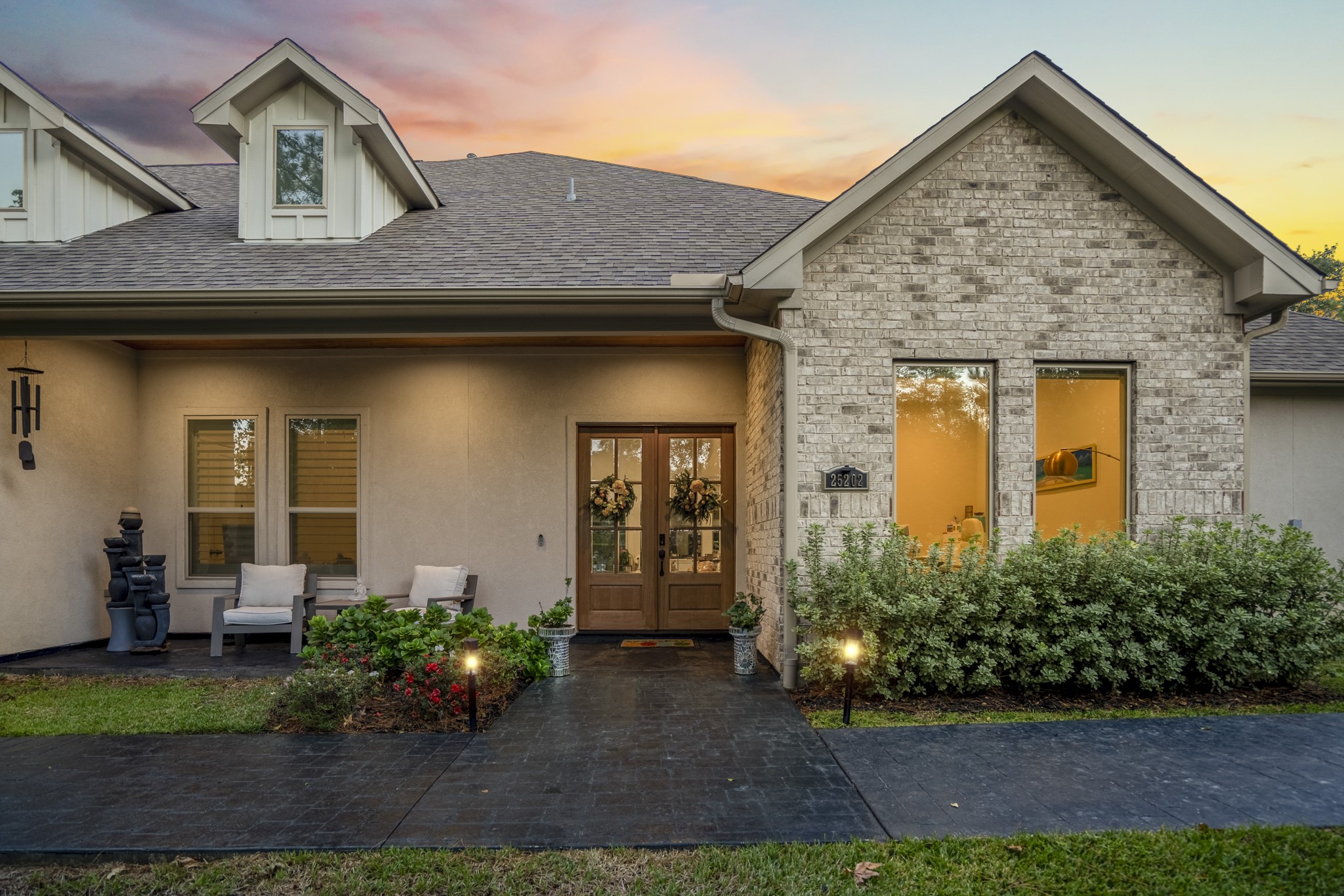 25202 Wilkes Park Road Tomball, TX 77375 - Photo 2 of 50 Elegant exterior lighting highlights the architectural lines and mature trees, creating a warm evening welcome.