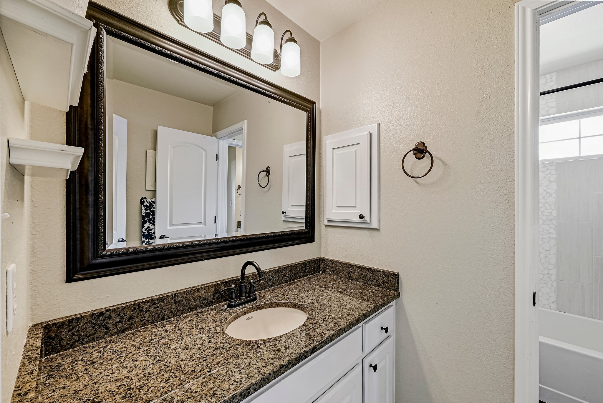 2408 Amen Corner Road Pflugerville, TX 78660 - Photo 32 of 40 Bathroom vanity featuring a speckled countertop, undermount sink, and dark bronze faucet