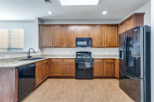 a kitchen with stainless steel appliances granite countertop wooden cabinets a stove a sink and a refrigerator