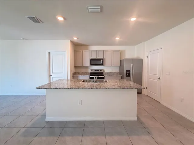 a kitchen with stainless steel appliances granite countertop a stove a sink a refrigerator a microwave and cabinets