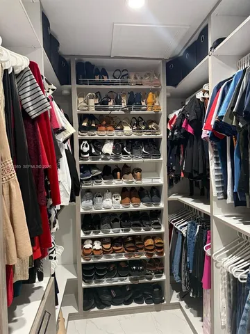 a view of walk in closet with clothes and shoes