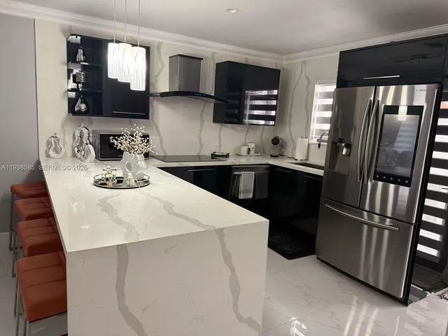 a kitchen with stainless steel appliances kitchen island granite countertop a refrigerator a sink a stove and cabinets