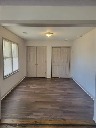 a view of an empty room with window and wooden floor