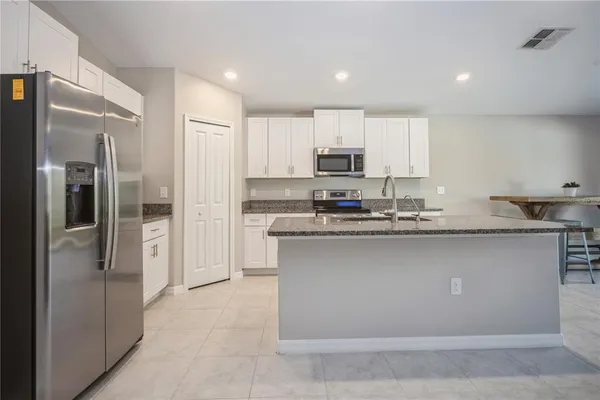 a kitchen with stainless steel appliances granite countertop a refrigerator a stove a sink and a oven