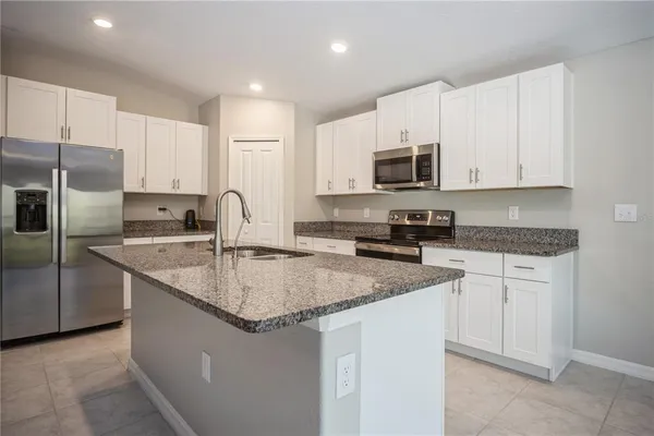 a kitchen with stainless steel appliances granite countertop a sink stove microwave and refrigerator