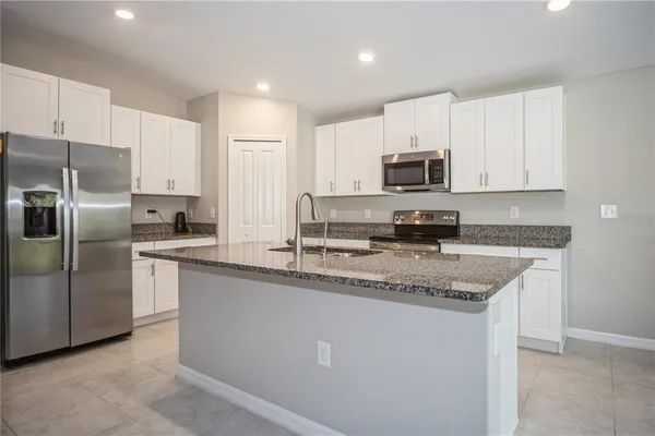 a kitchen with stainless steel appliances granite countertop a stove a sink a refrigerator a microwave and cabinets