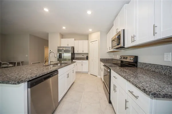 a large kitchen with stainless steel appliances granite countertop a sink stove and cabinets