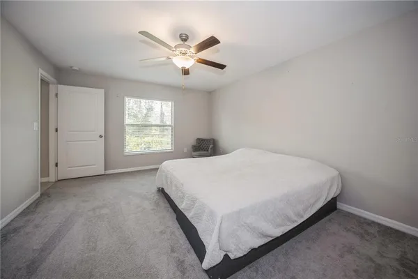 a bed sitting in a spacious bedroom next to a window