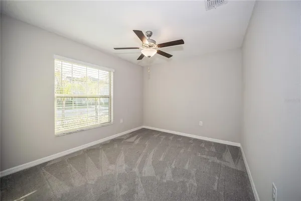 an empty room with a window and a fan