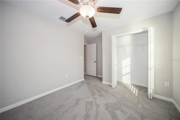 an empty room with closet and a chandelier fan
