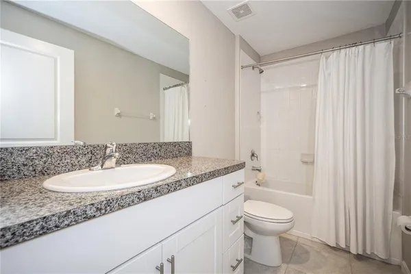 a bathroom with a granite countertop sink toilet a mirror a vanity and shower