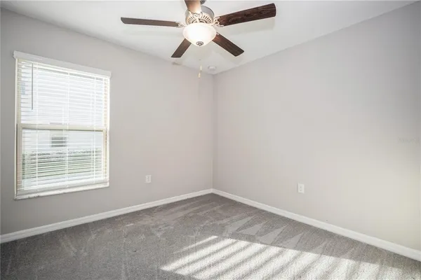 an empty room with a window and a fan