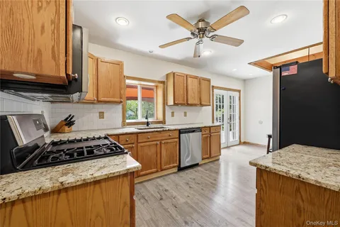 a kitchen with granite countertop a stove a sink dishwasher and a refrigerator with wooden floor
