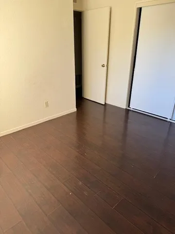 an empty room with wooden floor and entrance