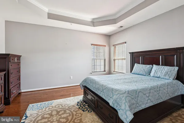 a spacious bedroom with a bed a dresser and windows