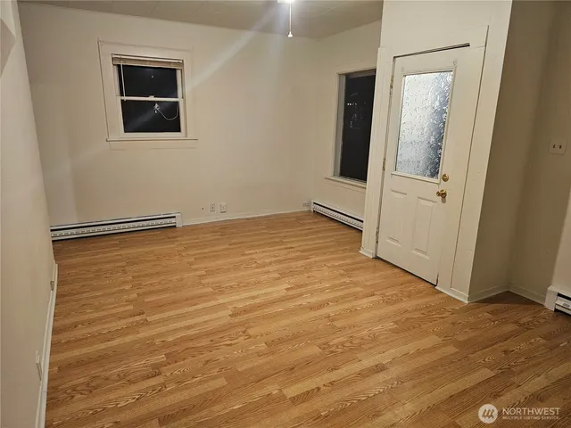 an empty room with wooden floor and mirror