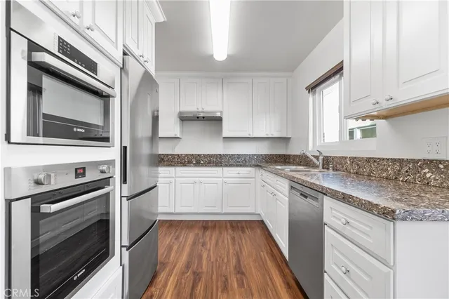 a kitchen with granite countertop cabinets stainless steel appliances and a sink