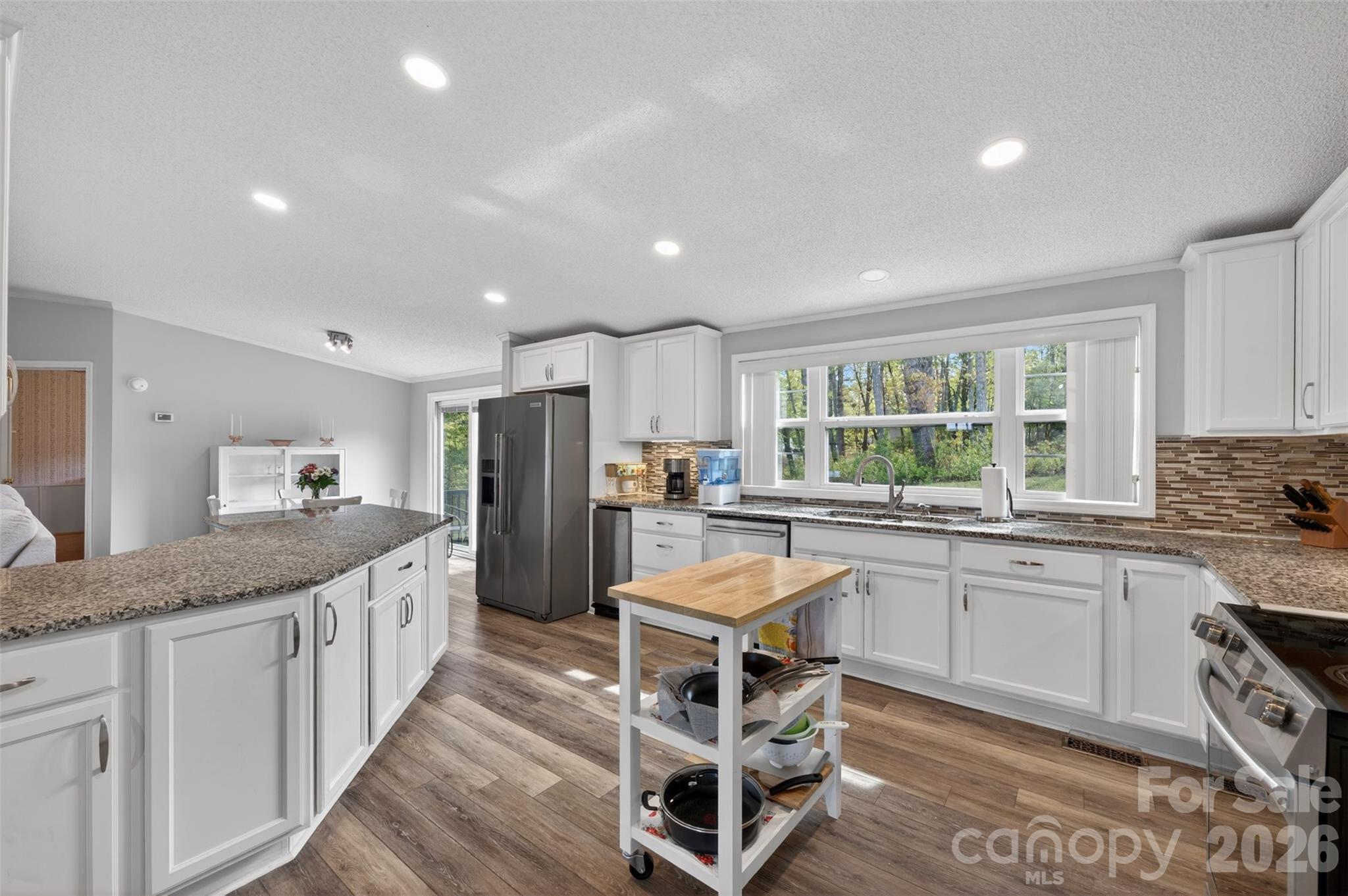 4352 Anderson Mountain Road Maiden, NC 28650 - Photo 14 of 42 a kitchen with stainless steel appliances granite countertop a stove top oven a sink dishwasher a dining table and chairs with wooden floor