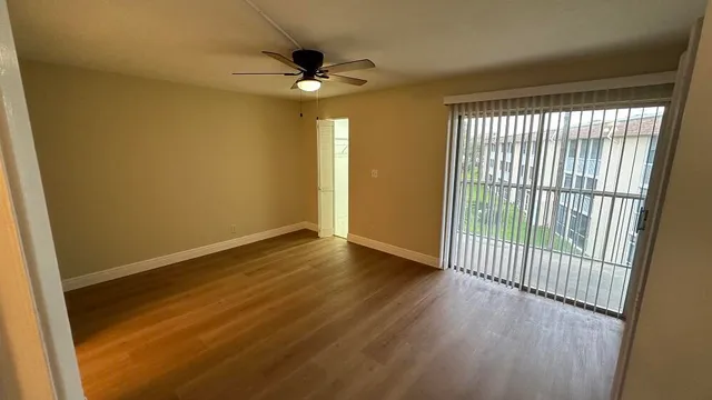 an empty room with wooden floor fan and windows