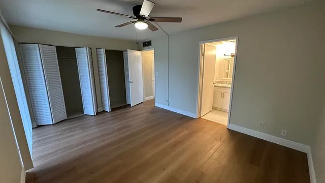 a view of empty room with wooden floor and fan