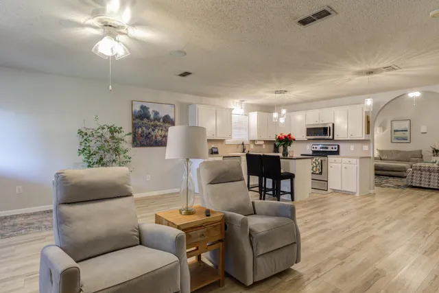 a living room with furniture kitchen view and a chandelier