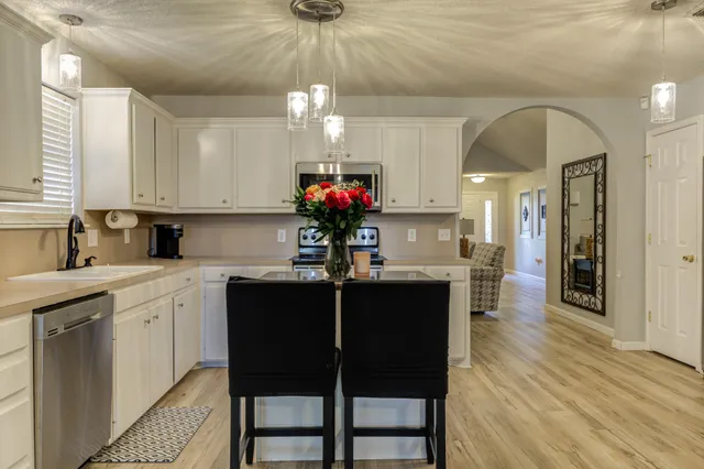 a kitchen with stainless steel appliances granite countertop a dining table chairs sink and cabinets