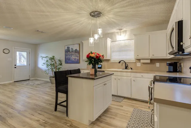 a kitchen with granite countertop a sink cabinets stainless steel appliances and a window