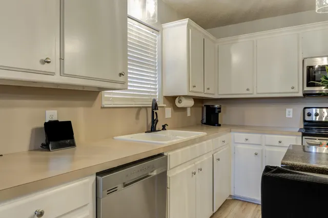 a kitchen with stainless steel appliances granite countertop a sink a stove and white cabinets
