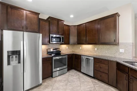 a kitchen with stainless steel appliances granite countertop a refrigerator and a stove top oven