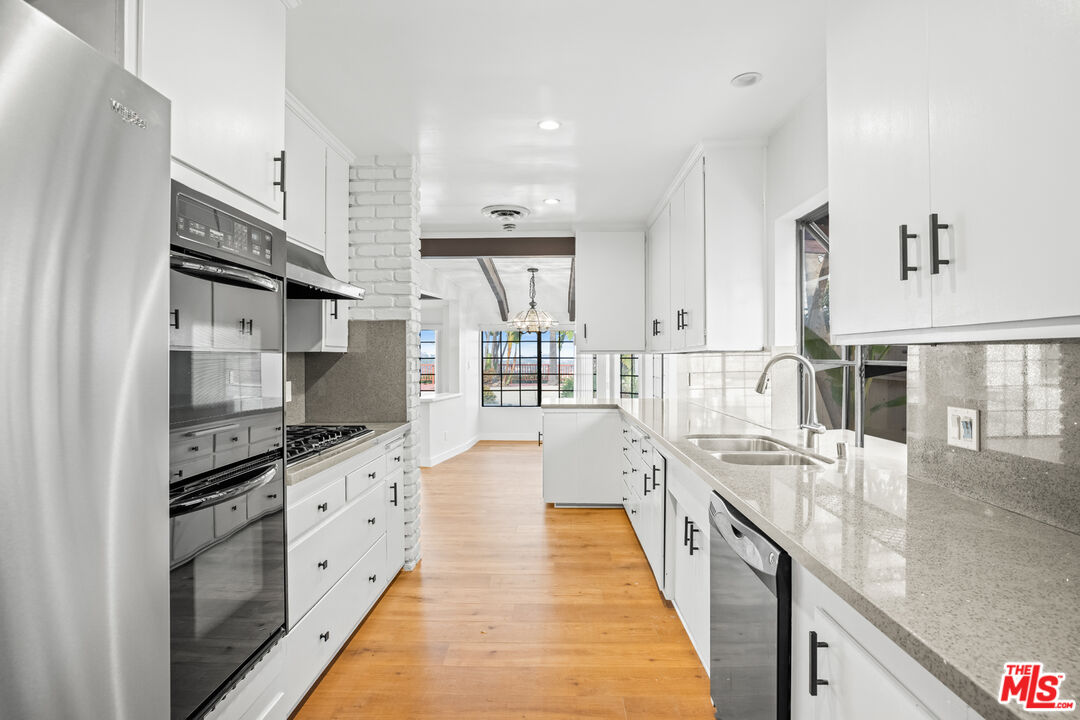 2254 Stradella Road Los Angeles, CA 90077 - Photo 13 of 27 a large kitchen with stainless steel appliances kitchen island granite countertop a large counter top a stove and a refrigerator