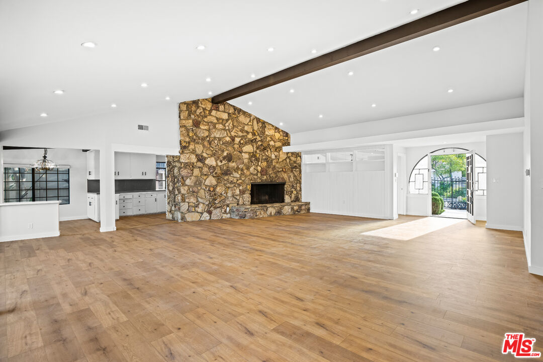 2254 Stradella Road Los Angeles, CA 90077 - Photo 8 of 27 an empty room with wooden floor fireplace and windows