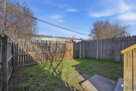 a view of a backyard with wooden fence and a bench