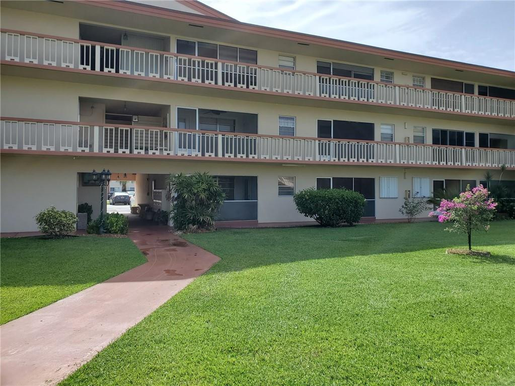 a front view of a building with a garden and plants